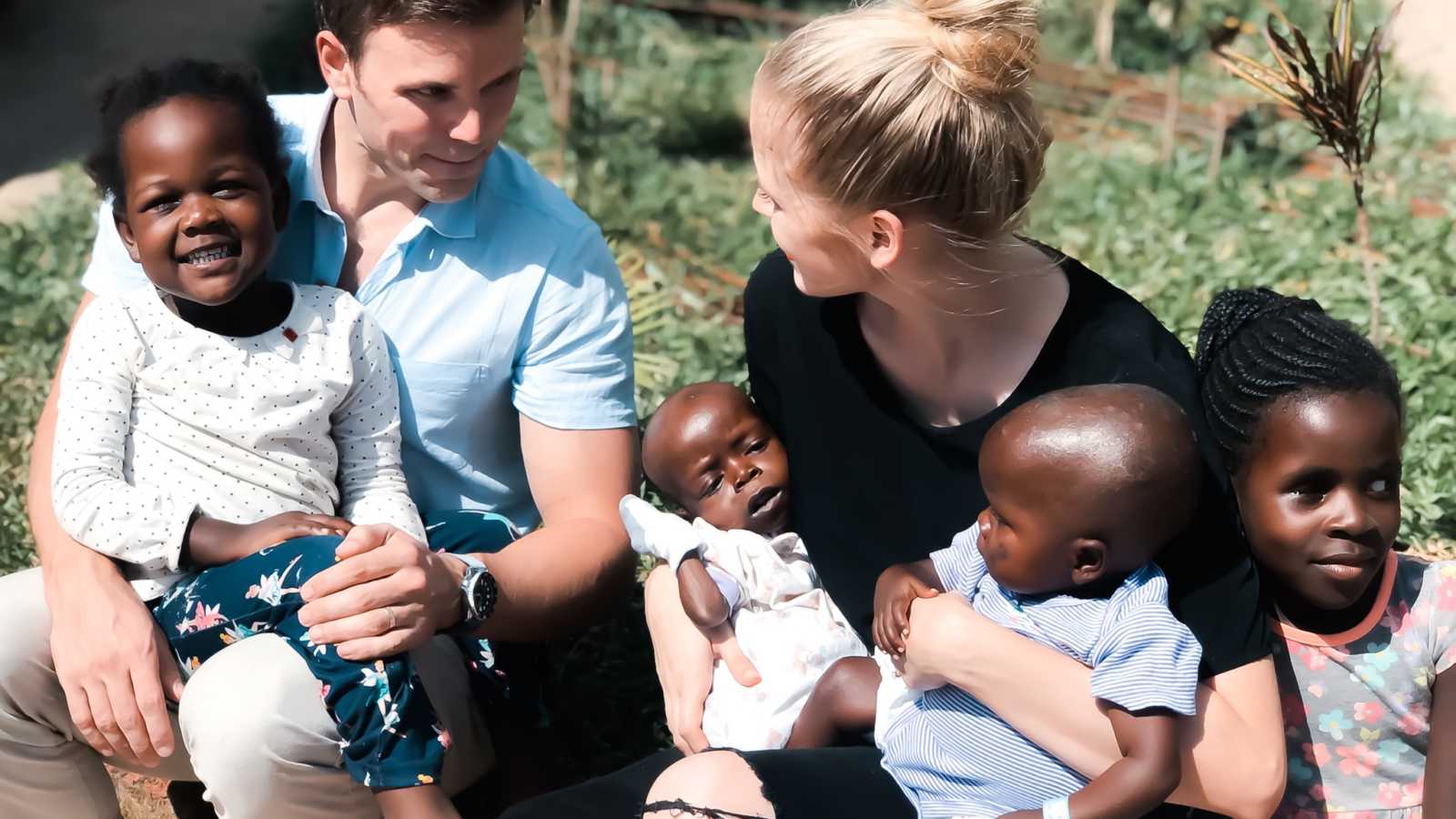 Husband and wife sits outside with four Kenyan orphans in their lap