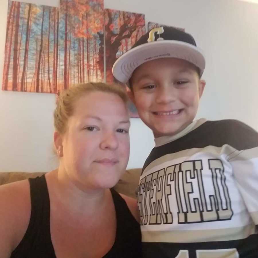Mother sits smiling in selfie with her second grade son in baseball uniform
