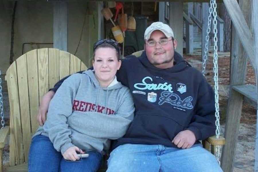 Woman who was told she may have to terminate her pregnancy sits outside on wooden swing with husband