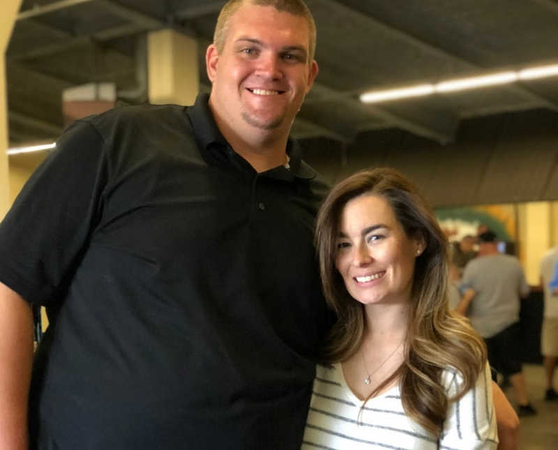 Husband who has overcome many blood clots stands smiling beside hemophiliac wife