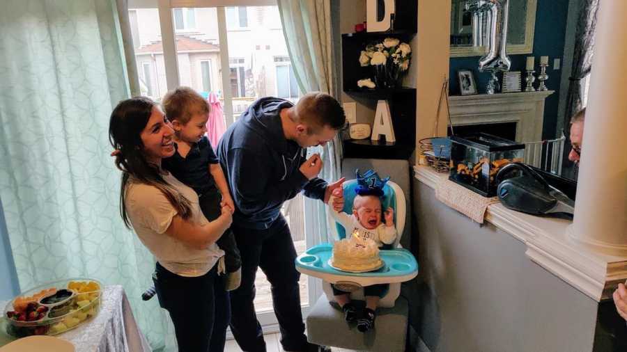 Mother who is done apologizing for putting her family first smiles as she holds son beside husband and baby in high chair