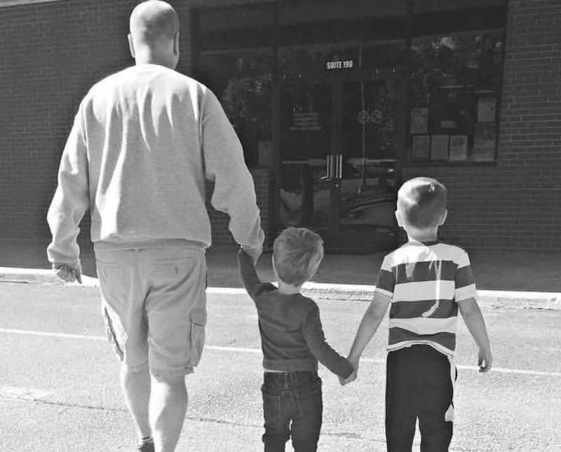 Alcoholic father walks into store holding hands with two young sons
