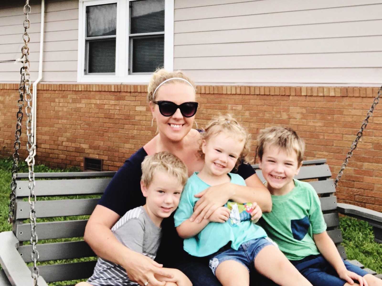 Mother who escaped abusive husband sits on outdoor swing with three young children