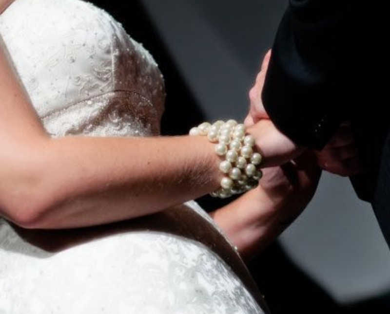 Close up of bride and groom holding hands