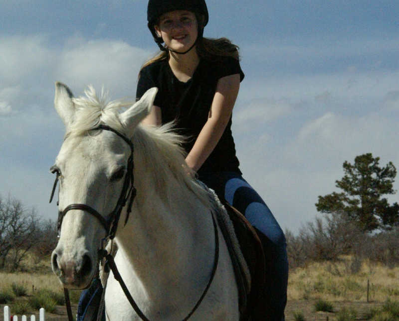 Teen smiling as she sits on white horse