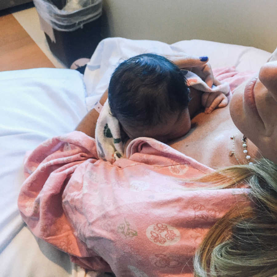 Newborn breastfeeds from mom who sits in hospital room