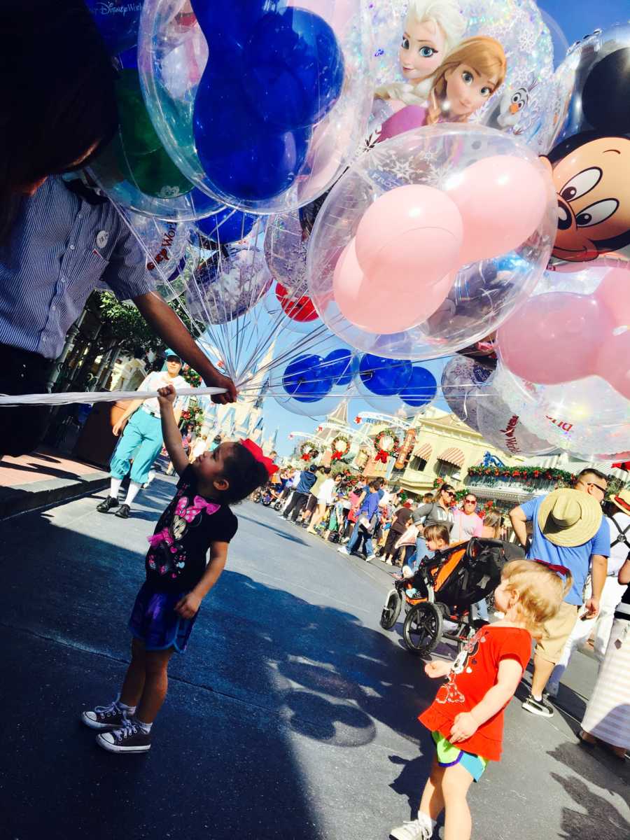 Little girls stand at Disney World looking up at balloons