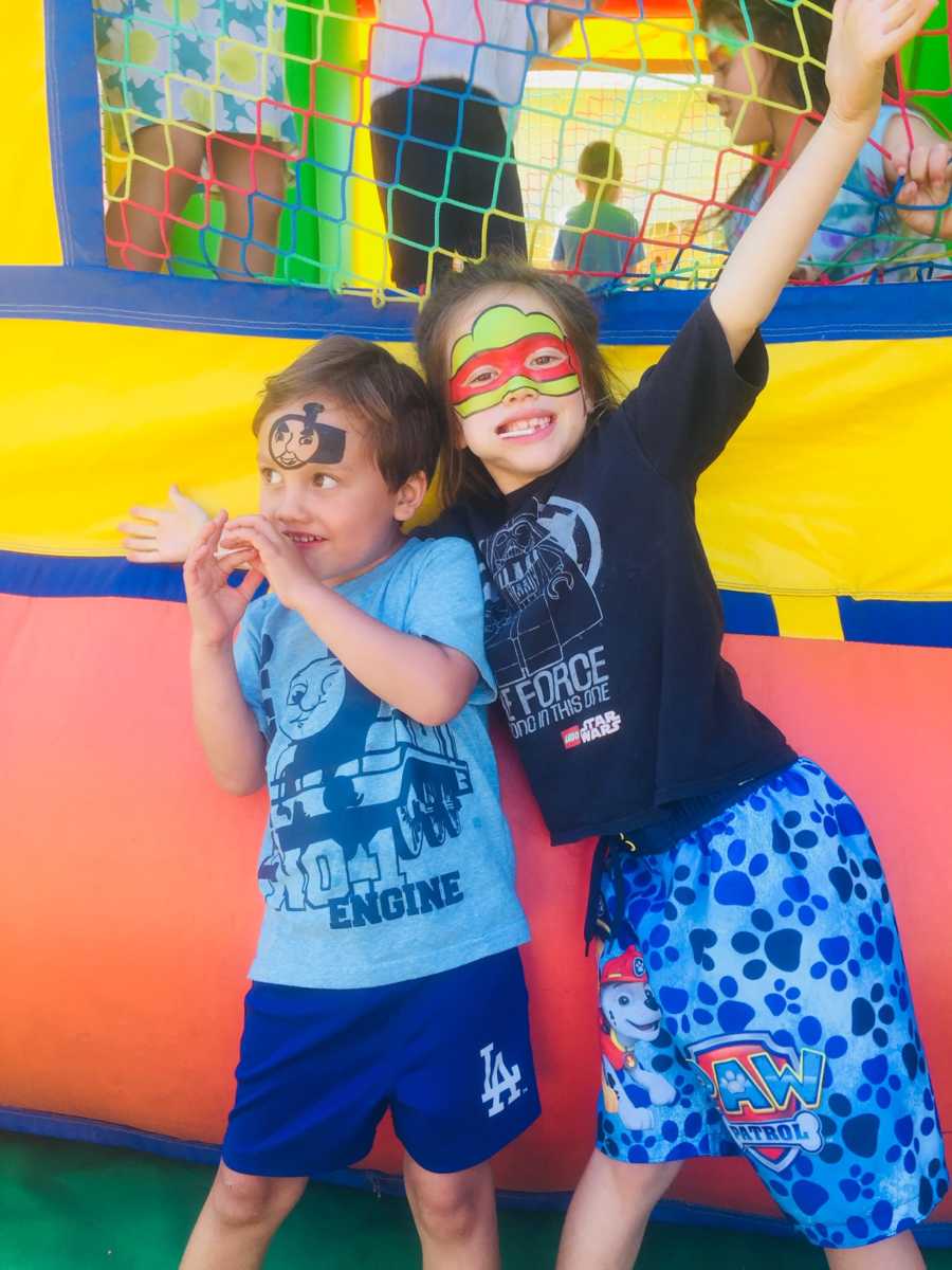 Brother and sister with their faces painted stand outside of bouncy house before being diagnosed with cancer