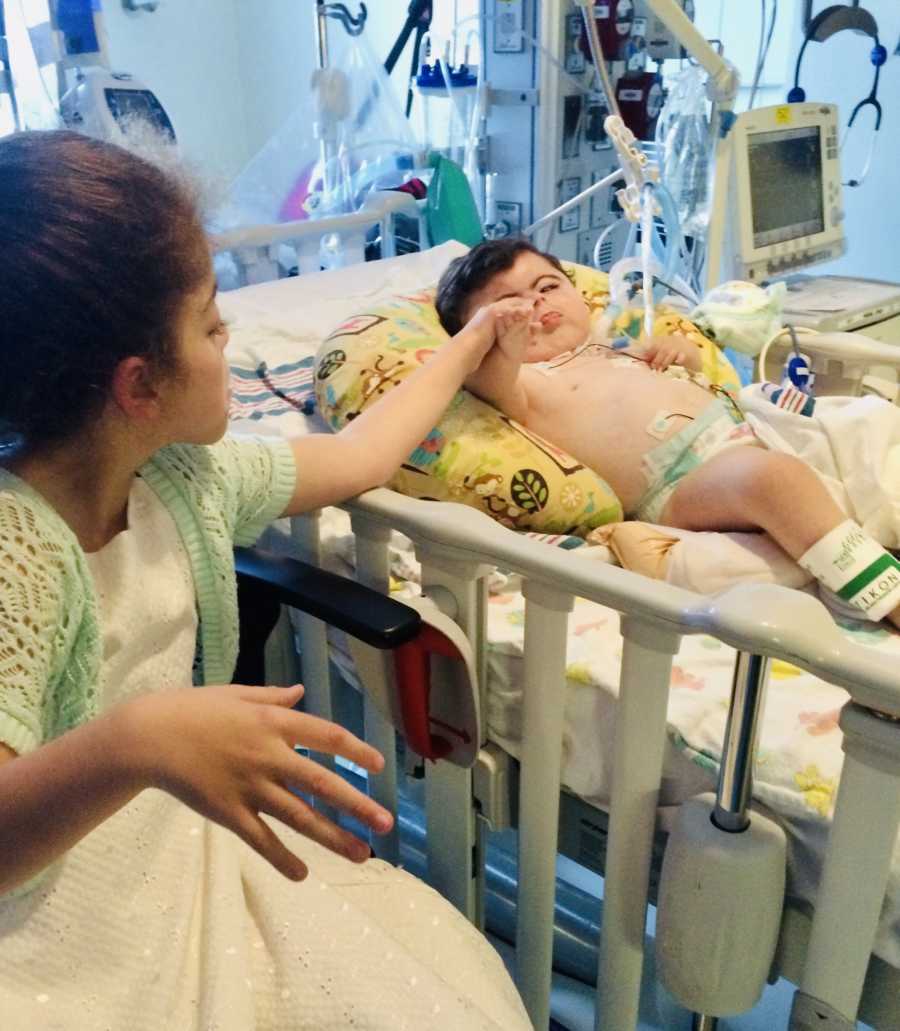 Baby in PICU with Cornelia de Lange Syndrome holds hands with special needs foster sister