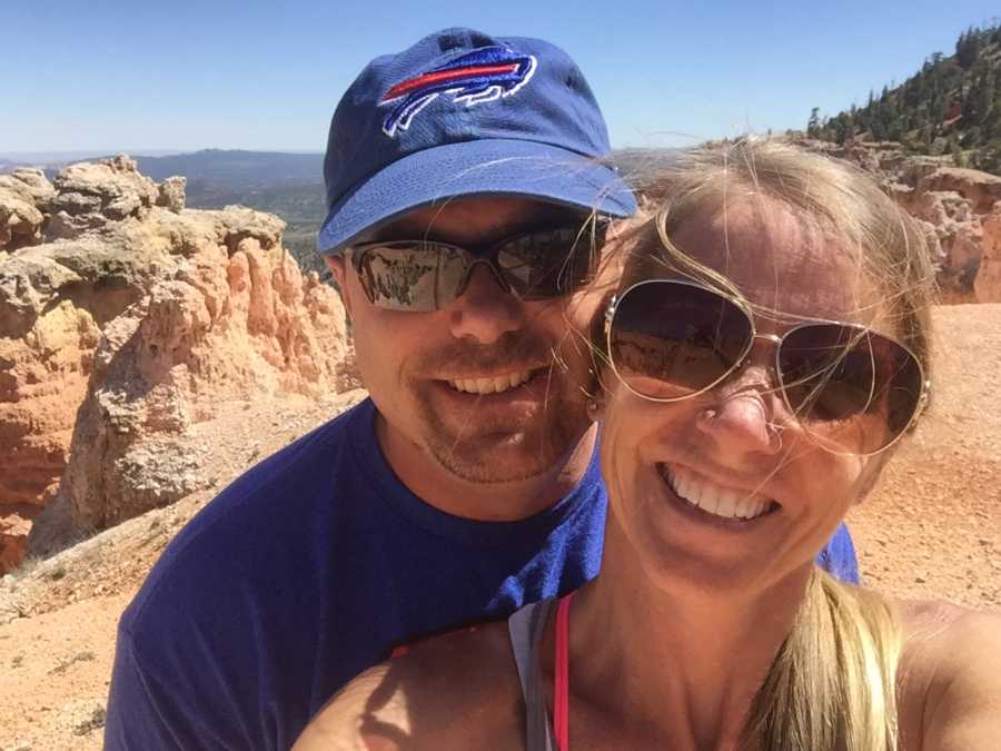 Woman smiles in selfie with husband with canyon in background