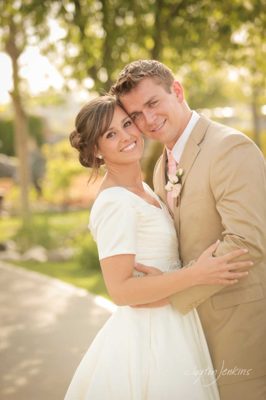 Bride and groom stands smiling holding each other