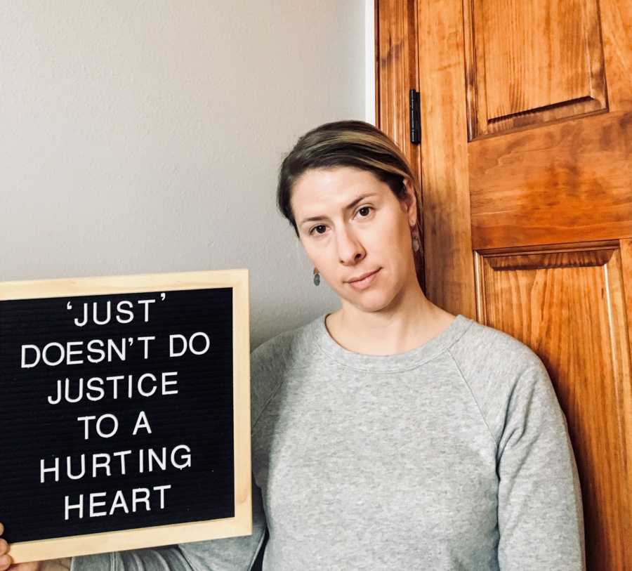 Woman that lost her baby holds sign that says, "Just doesn't do justice to hurting a heart"