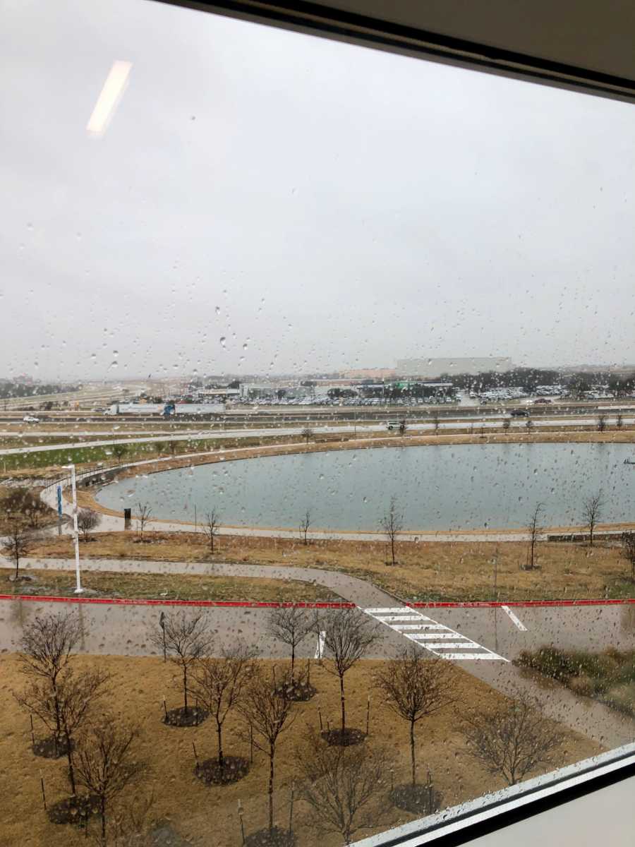 View from hospital window with water droplets on it that looks out to small body of water