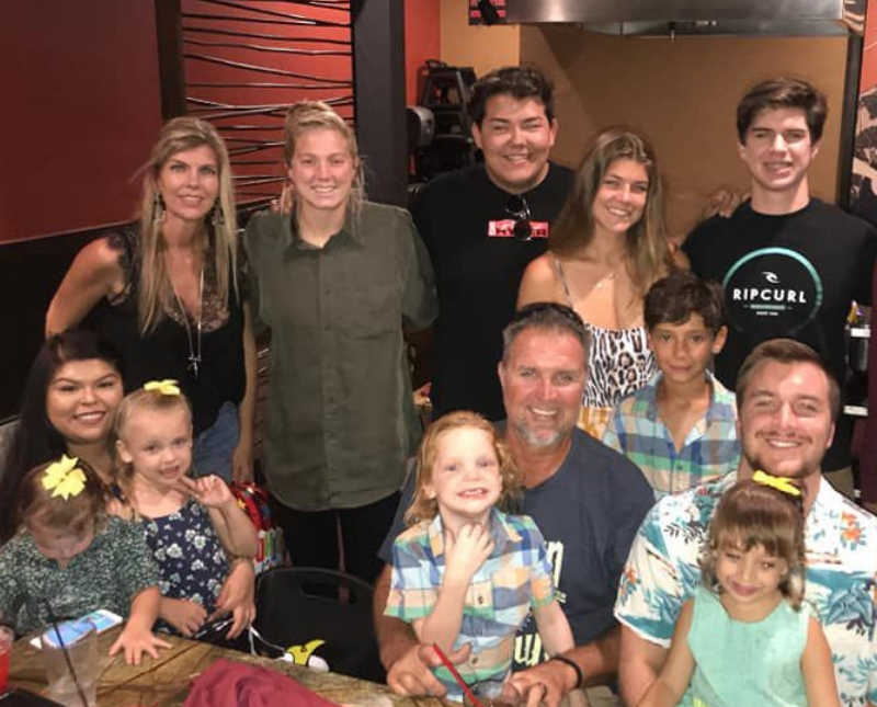 Woman who was declared permanently disabled stands smiling in restaurant beside friends and family