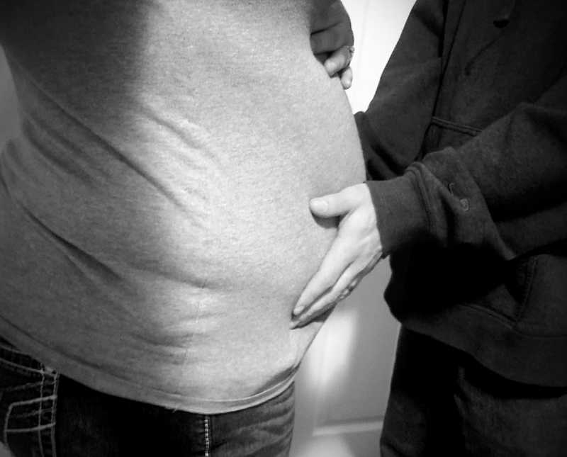 Husband stands holding pregnant wife's stomach