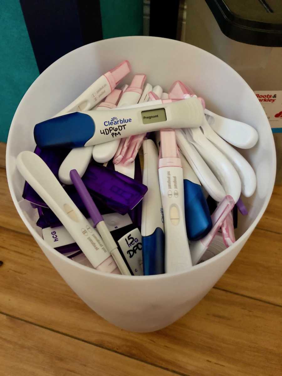 Trashcan of pregnancy tests with one on top saying, "pregnant"