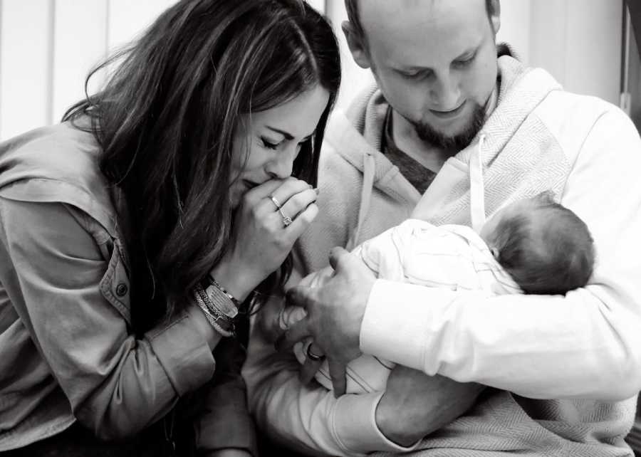 Father holds adopted newborn as his wife sits crying beside him