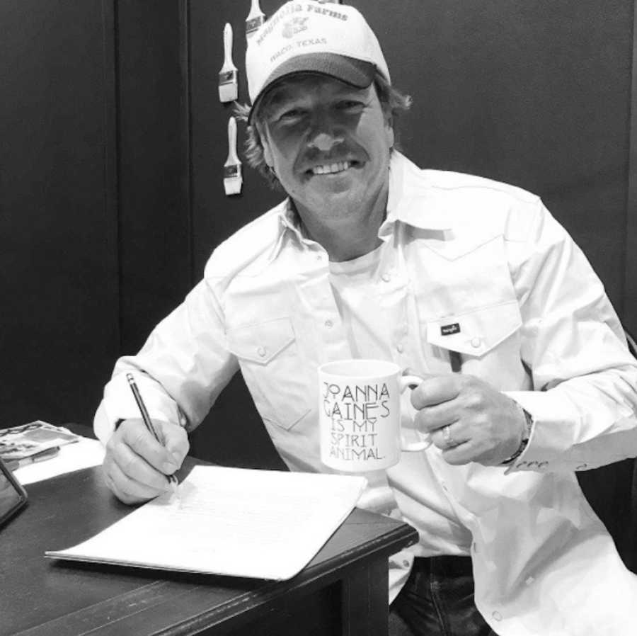 Chip Gaines smiling holding up mug that says, "Joanna Gaines is my spirit animal"