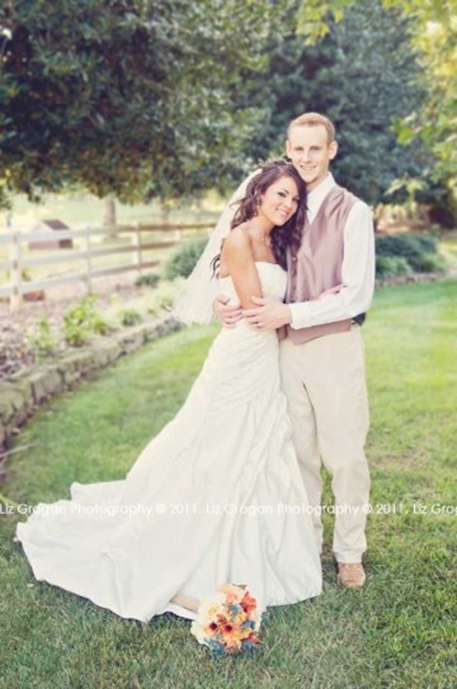 Bride and groom who beat Leukemia stand smiling outside in each others arms
