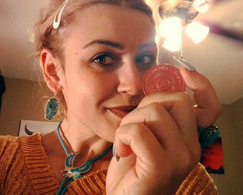 Woman takes selfie while holding her sober chip