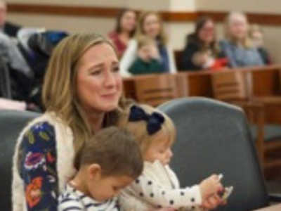 Woman cries as she sits at adoption court with two little kids in her lap