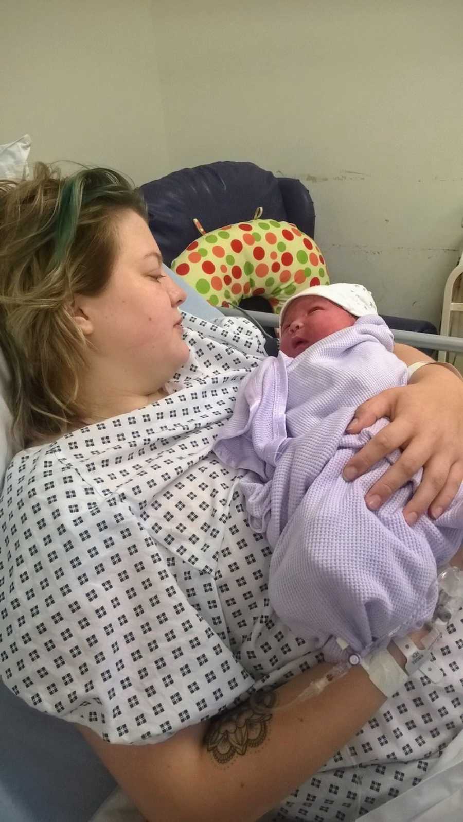 Woman lays in hospital bed holding newborn