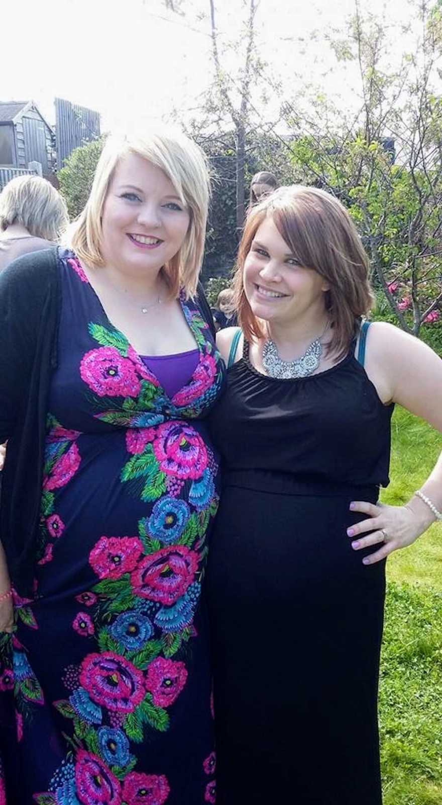 Sisters stand outside smiling in dresses