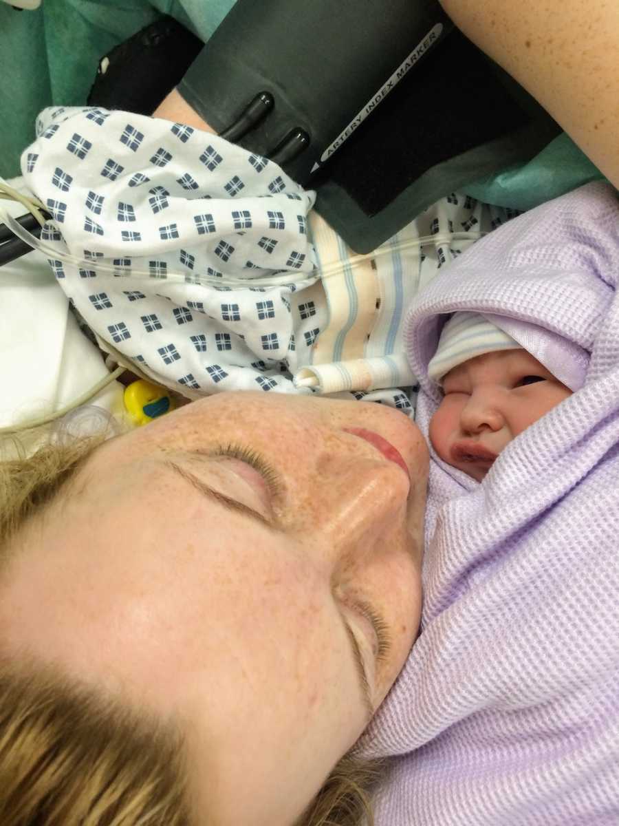 Mother who had material sepsis lays in hospital bed with newborn wrapped in purple blanket