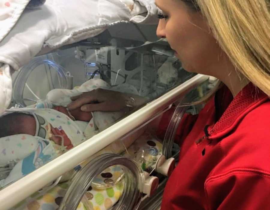 Mother touches adopted newborn that lays in NICU