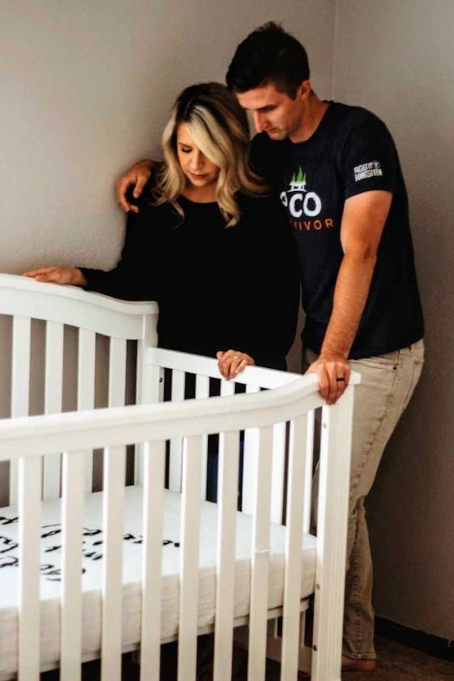 Husband and wife stands over crib meant for their adopted child