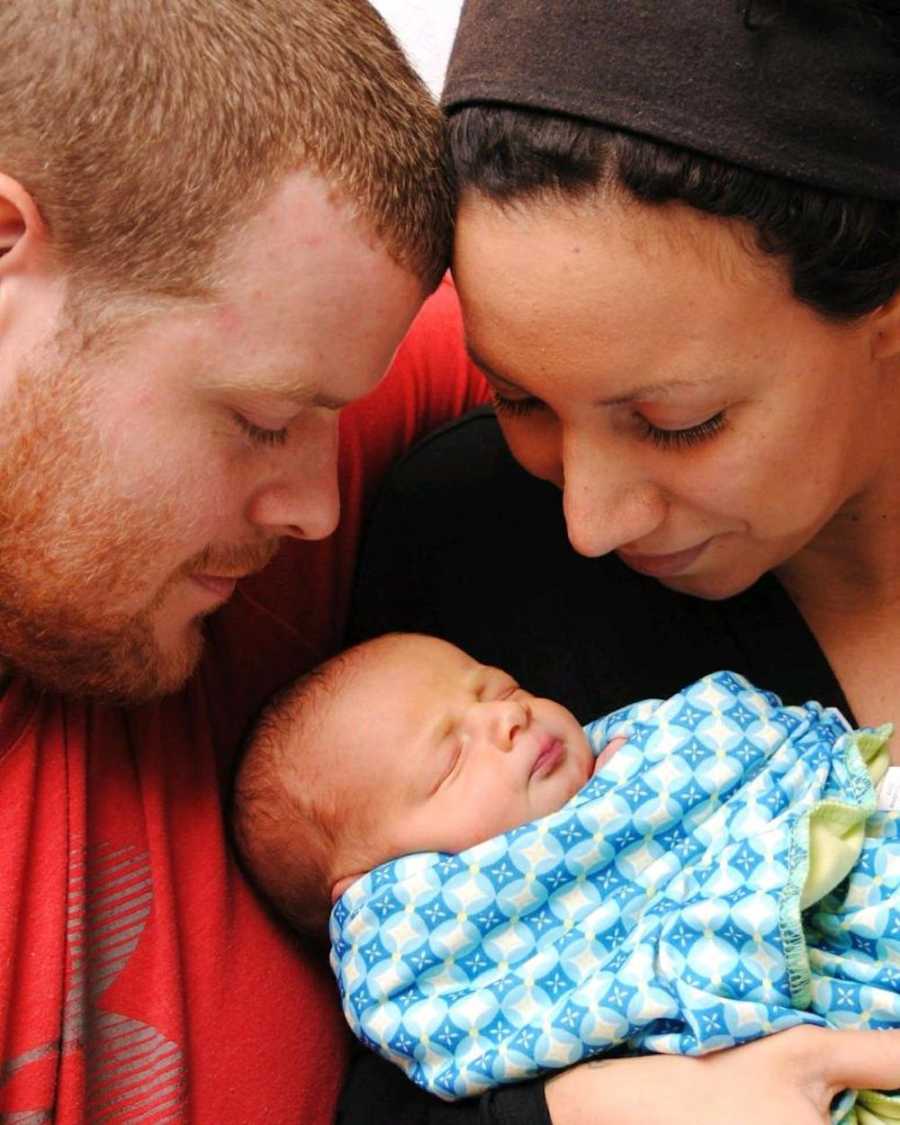 Woman who quit taking drugs to have child smiles at newborn in her arms with father of baby beside her