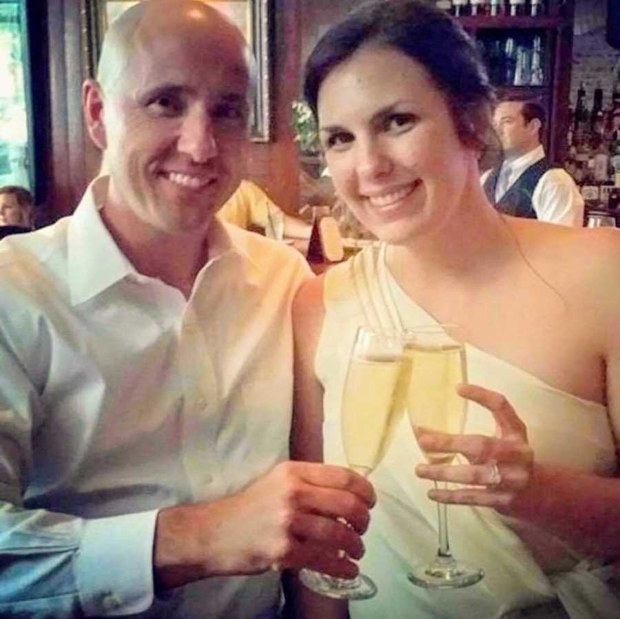 Engaged couple smiles as they cheers with glass of champagne