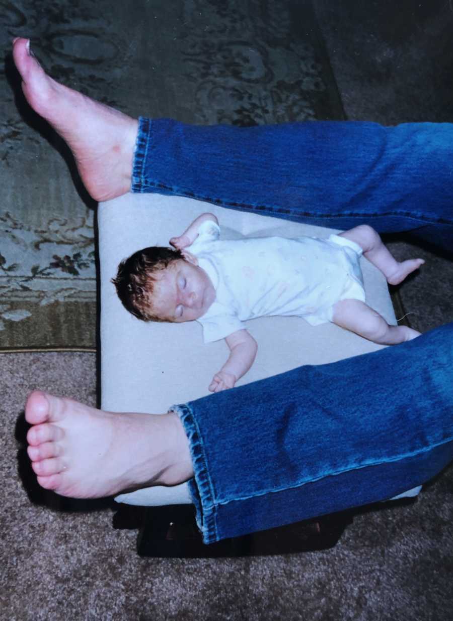 Baby lays on back on ottoman in between adults legs