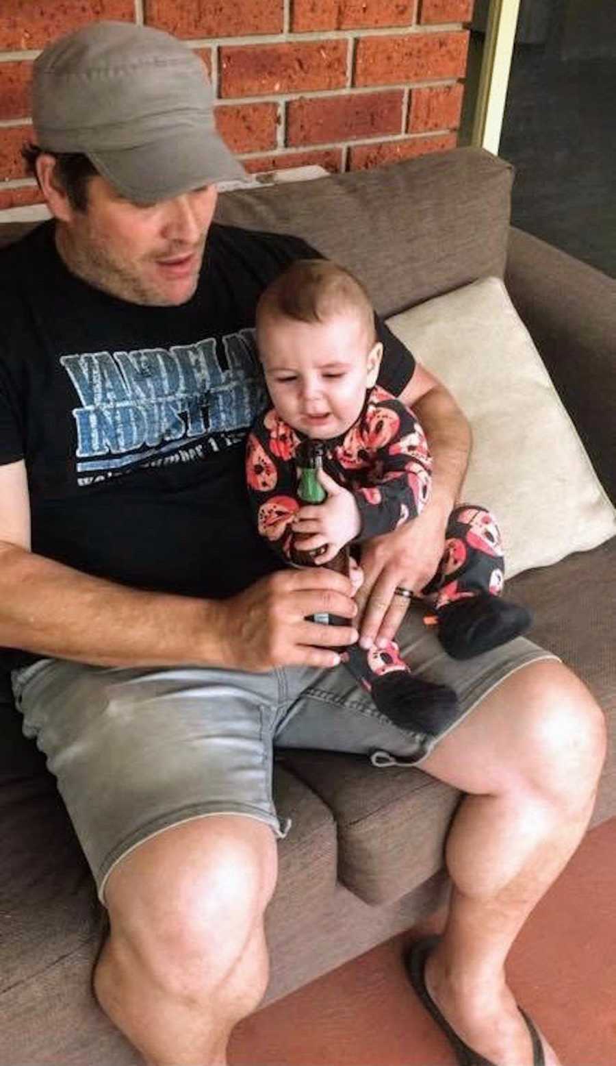Father sits on couch with baby boy in his lap