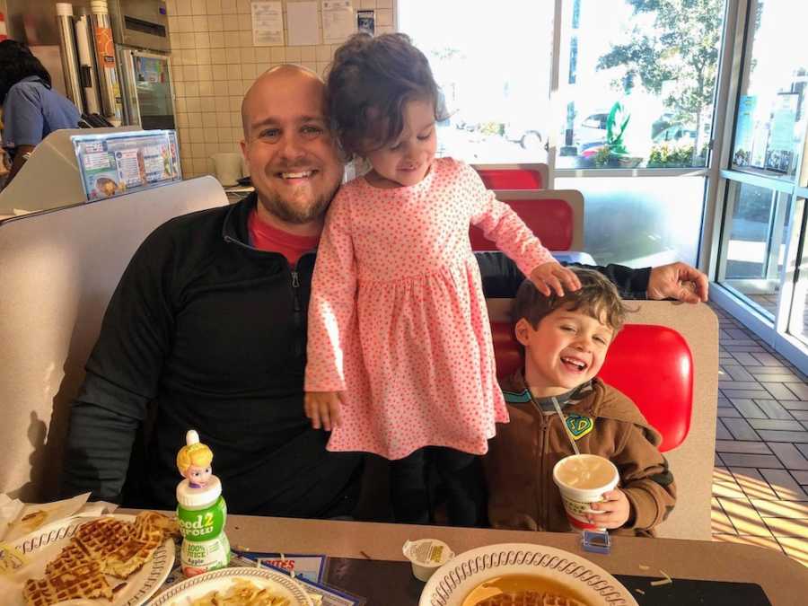 Father sits in booth of restaurant with his two young kids