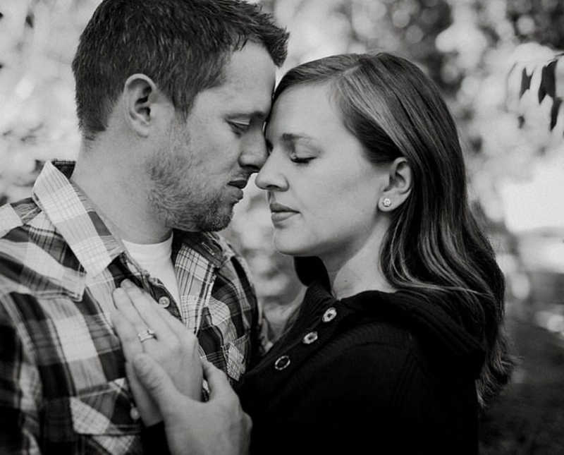 Woman places hand on fiancee's chest for engagement photos