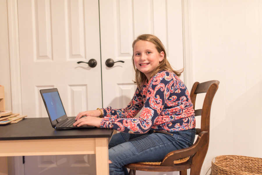 Young girls sits on laptop whose mother has put restrictions on it to protect her
