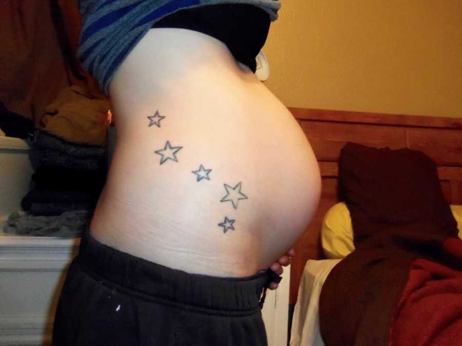 Image of pregnant woman's stomach with star tattoos on it