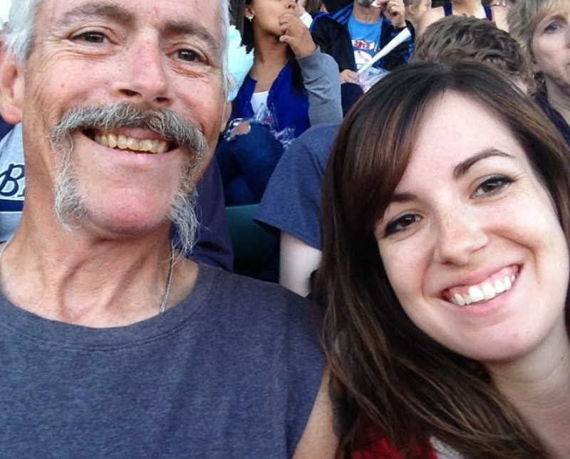 Woman smiles at sporting event in selfie with father who is an addict