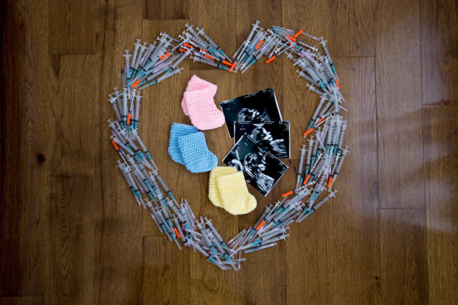 Ultrasound pictures of triplets beside three pairs of baby socks surrounded by IVF needles in heart shape