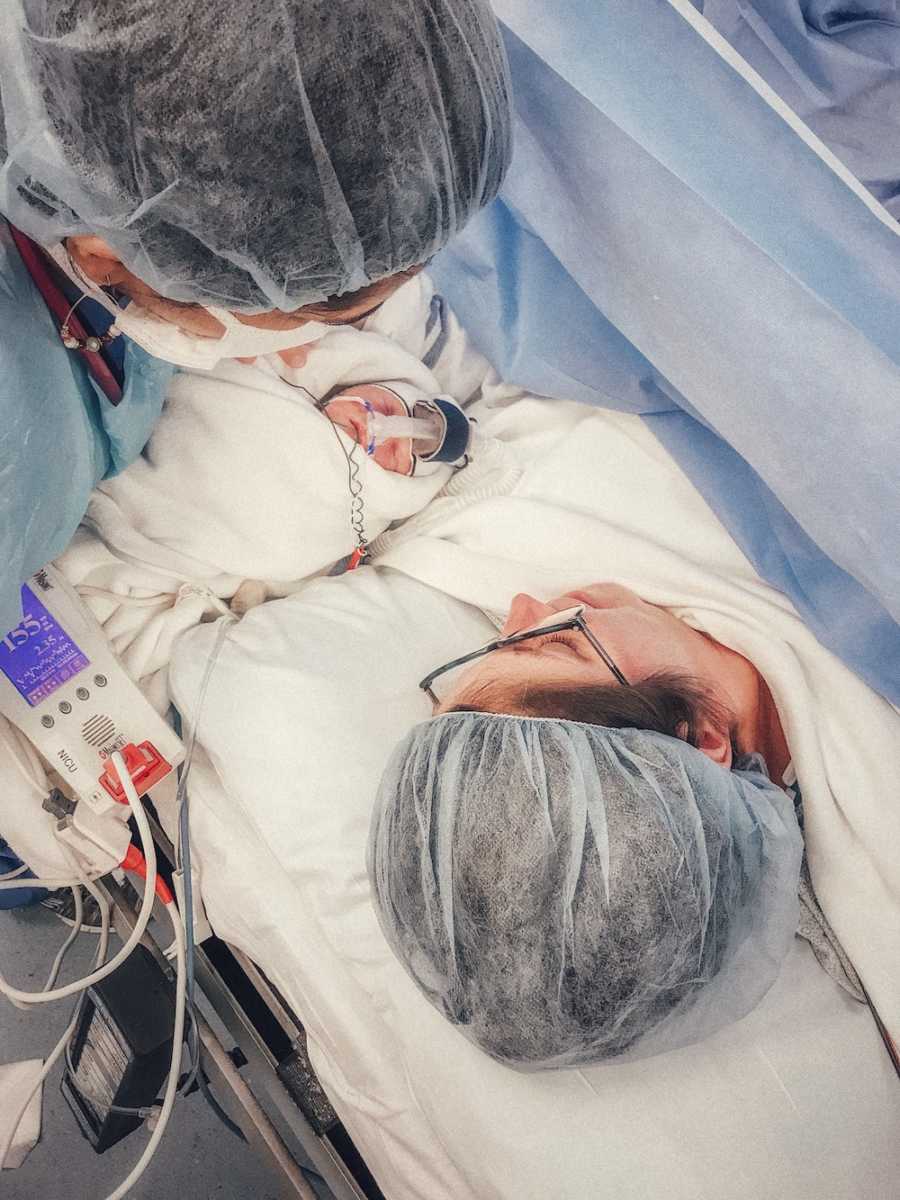 Nurse holds newborn for mother who had c-section to see