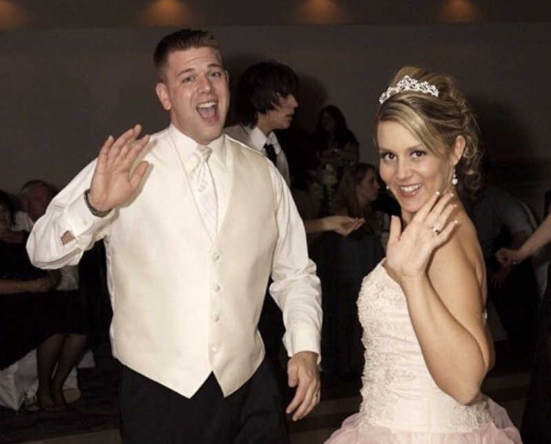 Bride and groom smile and wave at their wedding reception