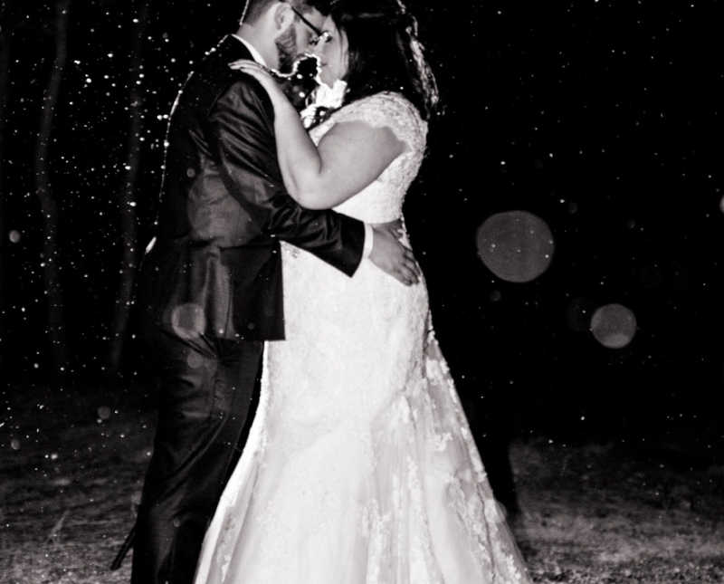 Bride and groom stand outside holding each other close