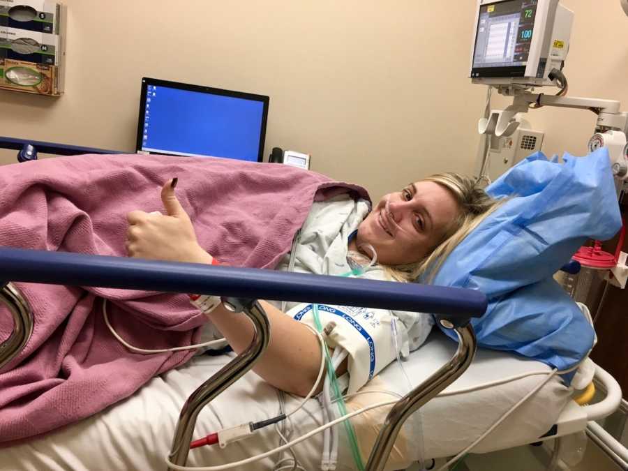 Woman laying in hospital bed with thumbs up awaiting to have her gallbladder removed
