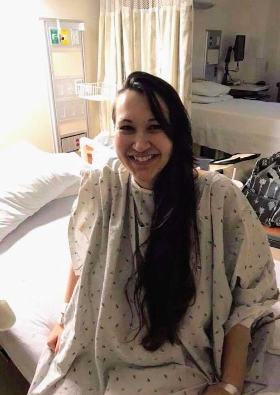 Mother with Acute B-Cell Lymphoblastic Leukemia sits on edge of hospital bed smiling
