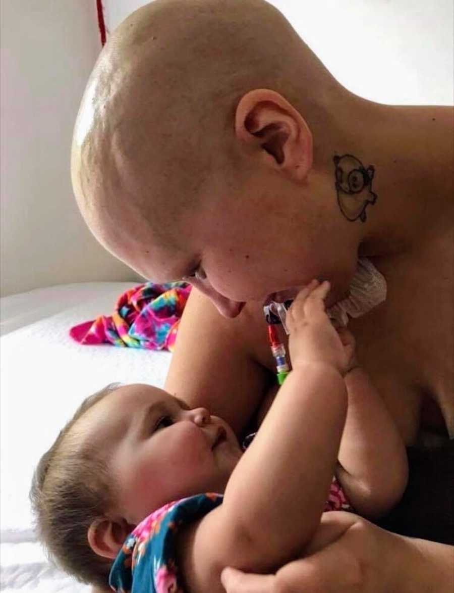 Mother with Acute B-Cell Lymphoblastic Leukemia leans over baby girl