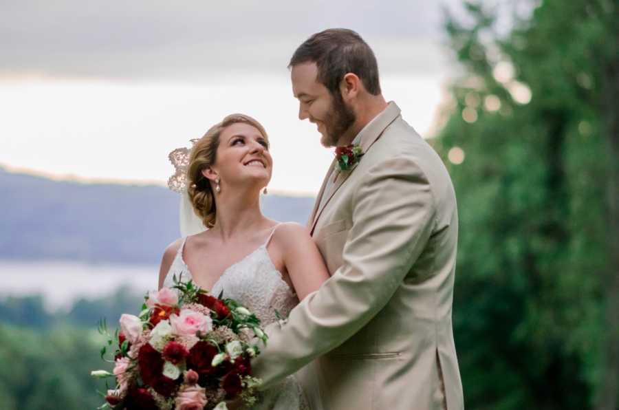 Bride and groom stand outside smiling at each other