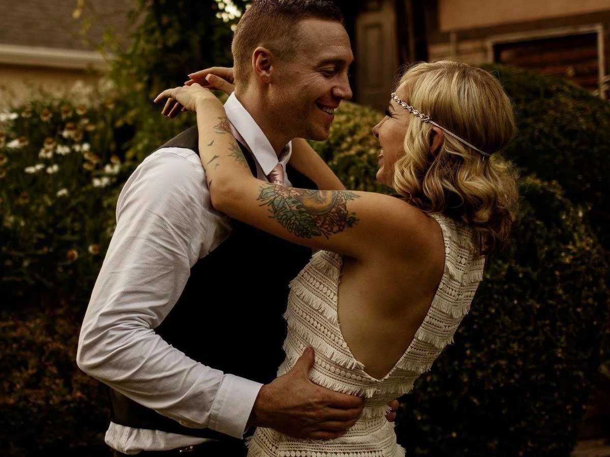 Bride smiles as she drapes arms around grooms' neck