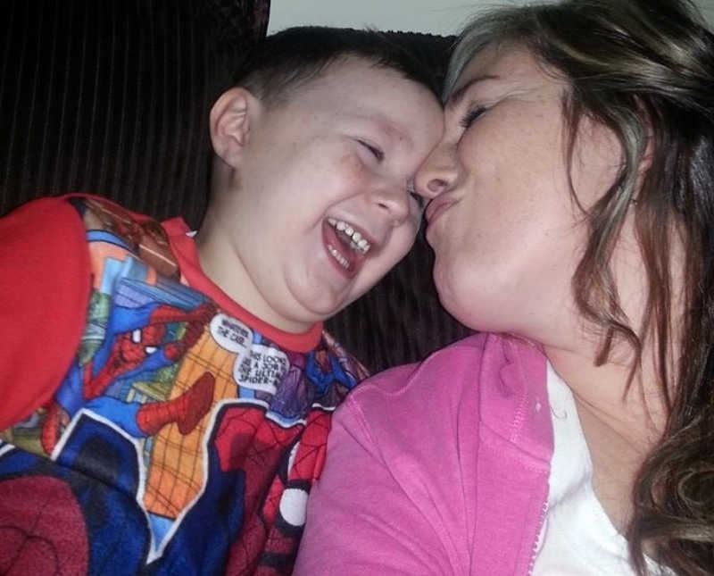 Mother makes kissy face at son who is sitting next to her smiling