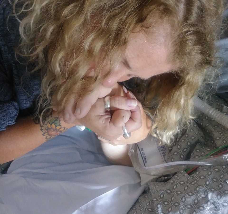 Woman rests head on her hand she holds with husband who has since passed from cancer